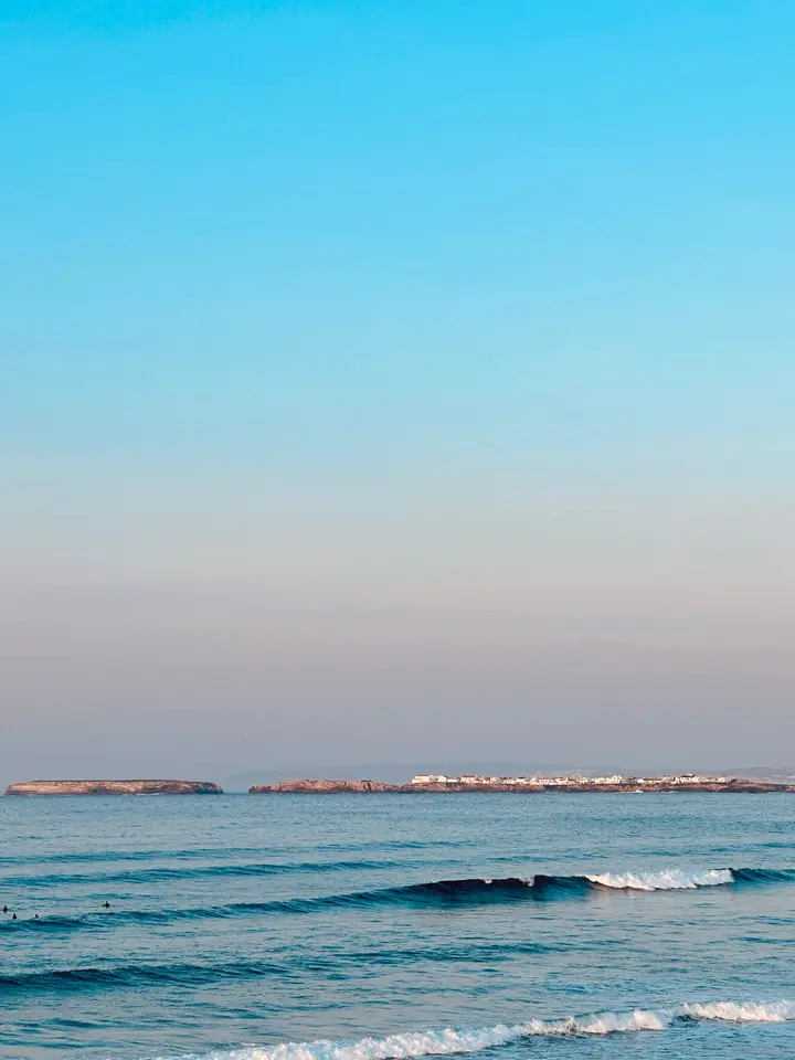 Calm morning ocean view towards Baleal island and surfers in the lineup